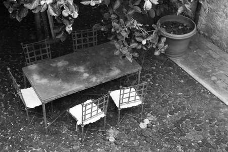 Wrought iron table seen from above in a typical Italian town. Leaves and lemons in the foreground.の写真素材