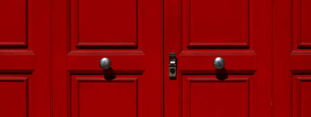 Portion of door in red lacquered wood with metal knobs and lock.