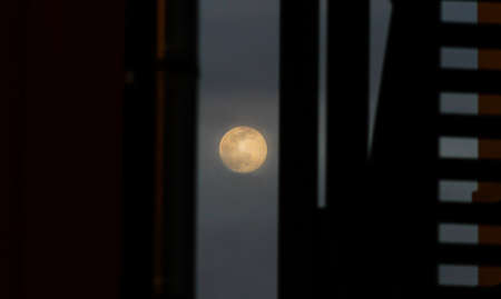 Full moon between a building and a flight of stairs against the light