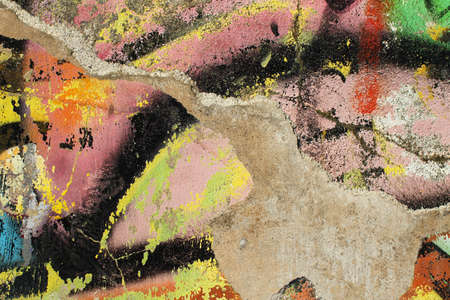 Detail of a ruined wall with traces of colored paint: green, orange, yellow, purple, black and white