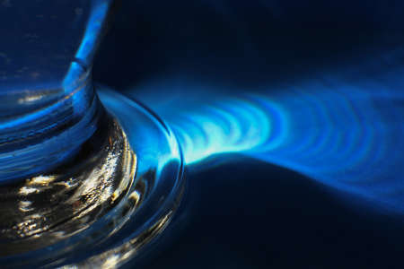 Macro photo, detail of glass with reflections and shadows on an intense blue surface.の写真素材