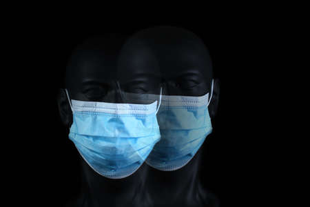 Double image of dark plastic mannequin head with face mask, black background.の写真素材