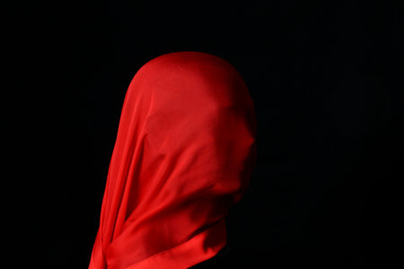 Mannequin head with large red silk scarf covering the face, black background.の写真素材
