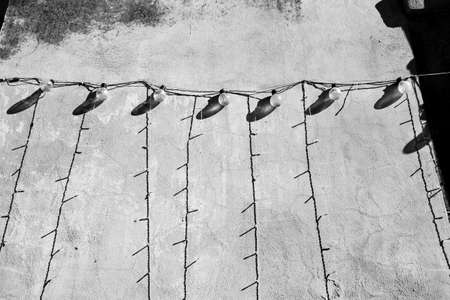 Rows of light bulbs along a wall, shadows and reflections, black and white photos.