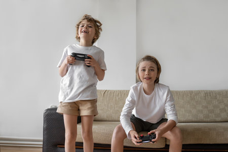 Funny caucasian siblings passionately playing video games in front of tv, two brother sister...
