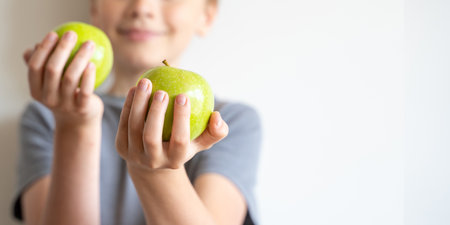 Smiling child held forward green apples in his hands over white background. Delicious and healthy...