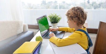 Child hands typing on the keyboard using laptop. distance learning online education. Schoolboy girl studying at home with digital tablet notebook and doing school homework. side view. copy spaceの写真素材