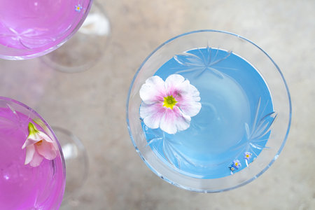 Top view on a glass with blue cocktail with tender flower. Selective soft focus. Copy space, negative space for design advertisementの写真素材