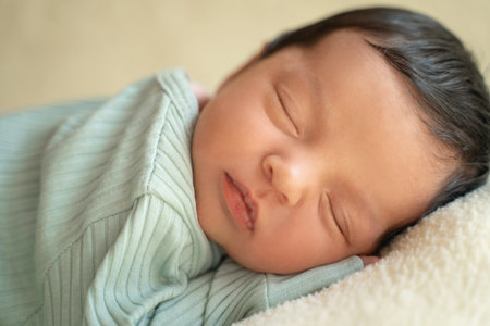 Newborn baby infant with dark hair lying on side sleeping awaking open eyes. Cute little Middle eastern child on blanket. Tranquil scene close upの写真素材