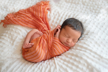 Newborn baby infant with dark hair lying on side sleeping awaking open eyes. Cute little Middle eastern child on blanket. Tranquil scene copy space for advertisementの写真素材