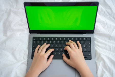 Close up smart caucasian middle School child using laptop green screen Chroma Key. Child typing on the keyboard. Online tutor teaching digital class, web lesson on computer at home. Virtual education. E-education. Schoolboy girl studying doing homework. Top viewの写真素材