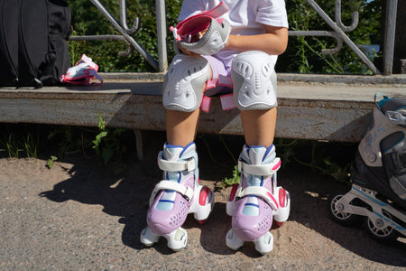 Child putting on inline skates rollers protection in public park in summer. Family leisure outdoor sport activity game. Copy spaceの写真素材