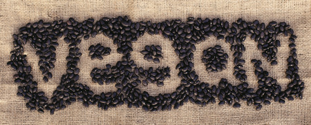 Organic black beans forming word vegan on the natural textile
