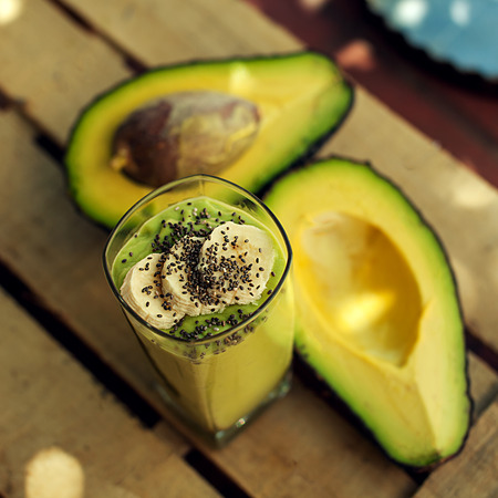 Avocado and banana smoothie or shake with chia from above on the wooden background with fresh...