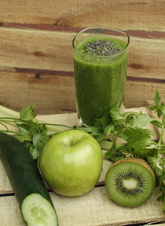 Fresh organic vegetables and fruits including cucumber, kiwi, apple, celery, parsley and green detox smoothie made of it with chia on wooden background. の写真素材