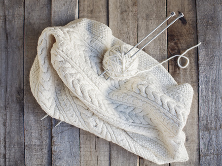 Beautiful cozy knitted and ball of wool with needles on wooden background. Hobbies. Top view.