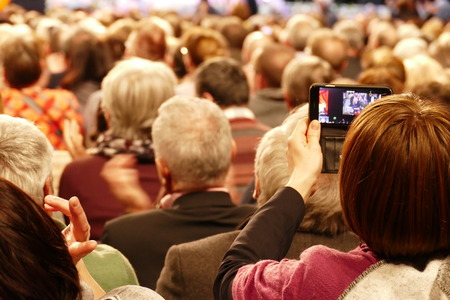 Lots of heads from behind. They are attending a concer