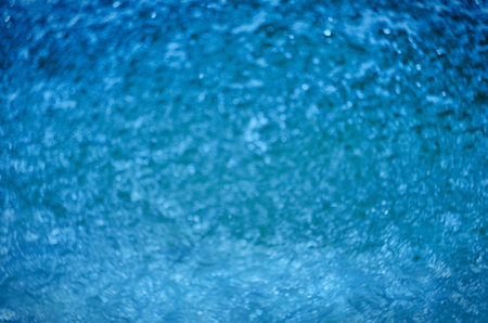 Blurred natural background of blue water with bokeh and sun reflectionsの写真素材
