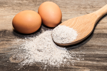Two eggs and flour on a spoonの写真素材