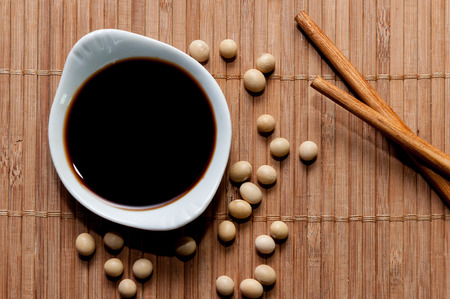 A bowl of soy sauce, soy grains and chopsticksの写真素材