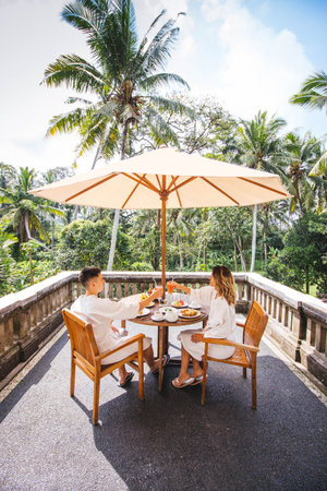 Young Couple Having Breakfast On The Terrace With The Jungle View In Bali, Indonesiaの写真素材