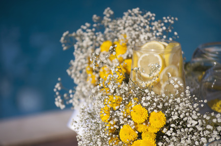 Wediing decoration with gipsofila and lemon in glass vase on the table near the outdoor poolの写真素材