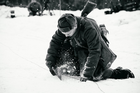 NELIDOVO, MOSCOW REGION, RUSSIA - JANUARY 22, 2017: Reconstruction of the winter defensive battles of the Red Army of the 1st Ukrainian Front in WWII called "Battlefield. Hot snow" (1944 year). The Red Army signalman equips his position. Black and white pのeditorial素材
