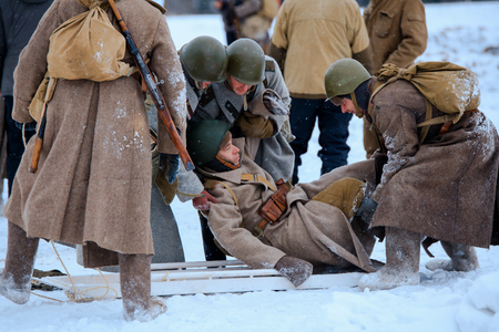 NELIDOVO, MOSCOW REGION, RUSSIA - JANUARY 22, 2017: Reconstruction of the winter defensive battles of the Red Army of the 1st Ukrainian Front in WWII called "Battlefield. Hot snow" (1944 year). Red Army medics in action with the injured soldier.のeditorial素材
