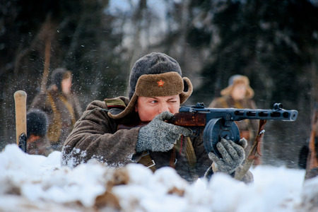 NELIDOVO, MOSCOW REGION, RUSSIA - JANUARY 22, 2017: Reconstruction of the winter defensive battles of the Red Army of the 1st Ukrainian Front in WWII called "Battlefield. Hot snow" (1944 year). Red Army infantry soldier shooting his PPSh submachine gun.のeditorial素材