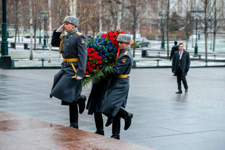 MOSCOW, RUSSIA - DECEMBER 04, 2019: The Honor Guard of the 154 Preobrazhensky Regiment in the infantry uniform laying flowers to the Tomb of Unknown soldier and Eternal flame in Alexander garden near Kremlin wall in rainy weatherのeditorial素材