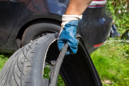 recycle of wheels.  the hand of the master in a blue glove holds the torn tire. on the background...