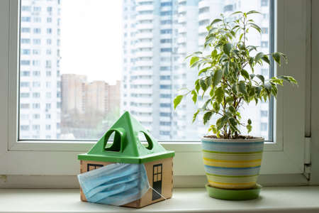 protection of the family from the pandemic of coronavirus covid -19. a toy house in a medical mask...