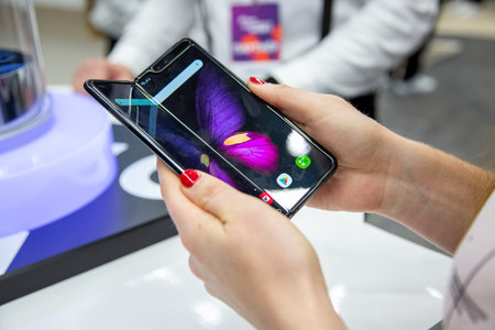 Moscow, Russia - October 04, 2019: female hands holding a new flagship smartphone Samsung Galaxy Fold with flexible display. close up. backgtound in blurのeditorial素材