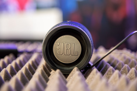 Moscow, Russia - October 04, 2019: Moscow, Russia - October 04, 2019: close up of black portable waterproof bluetooth music speaker JBL Charge 4 rests on noise reduction cover. side view, soft focus, background in blurのeditorial素材