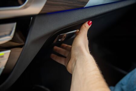 woman's hand opens a glove box in a black car interior. close-up, soft focus.の写真素材