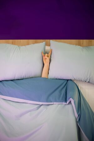Rock & roll, heavy metal, sign, horns party hard shows a female hand lying on a pillow from under...