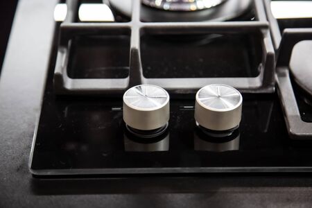 gas stove burner knobs with black mirror surface of cooker and stainless steel grills. top view,...