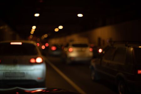 abstract traffic jam in the tunnel in bokeh blur, cars with red brake lights are standing, view from the car.の写真素材