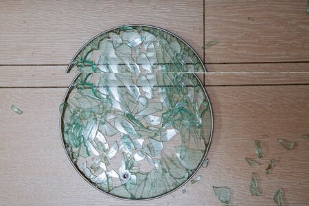 A close-up of a broken glass lid lies on a stake of tile. shards of glass shine. soft focus, top...