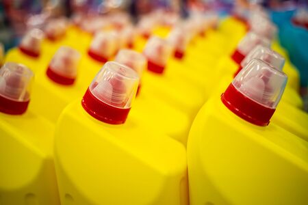 rows of yellow plastic bottles with a red cap wirh household chemicals. close up, soft focus, backgound in blurの写真素材
