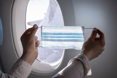 concept flights to asia coronavirus epidemic. close-up female hands holding a medical mask against...
