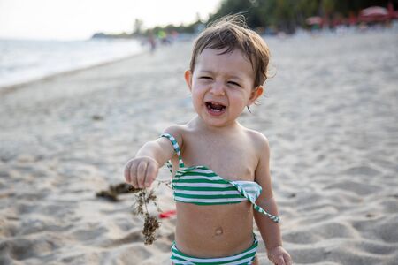 cute toddler kid holds out seaweed in the camera and screams scared