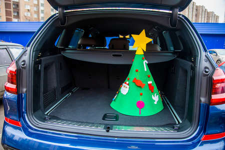 visit family in new year holidays concept. A felt Christmas tree decorated with toys and a star is standing in the empty luggage compartment of a modern crossover near copy space. close-up, soft focusの写真素材