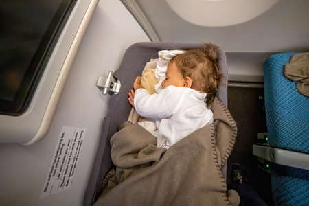 the infant passenger safely and comfortably sleeps in the baby bussinet on a long flight.の写真素材