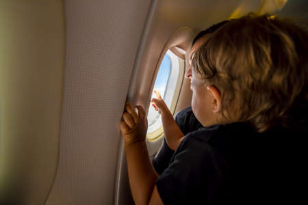 father and cute toddler sky at porthole. first flight concept, traveling with childrenの写真素材