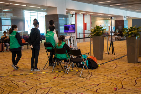 SINGAPORE - JULY 21.2020: Changi airport staff sit behind a thermal imager at a temperature control...