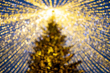 Christmas holiday blur background. Christmas tree in shining garland at New Year's outdoor marketplace fair in blurの写真素材
