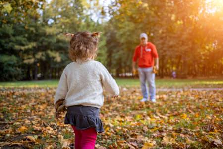 little toddler girl plays with father outdoors in autumn park ..の写真素材