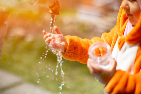 adorable toddler plays with water and tap in the sunshineの写真素材