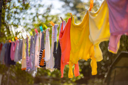Baby cute clothes hanging on the clothesline outdoor. Child laundry hanging on line in garden on green background.Baby accessories.の写真素材